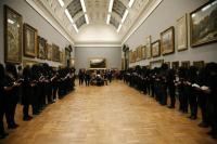 People dressed in black stand in large gallery