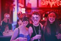 Three masked women at a drinks party