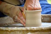 Photo of someone throwing clay on a wheel