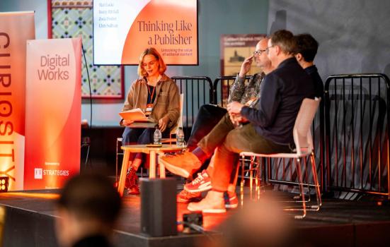 Delegates sitting on a stage with banners for Digital Works conference