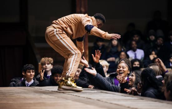 Actor on a thrust stage performing to young people