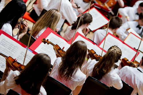 children playing violins in an orchestra