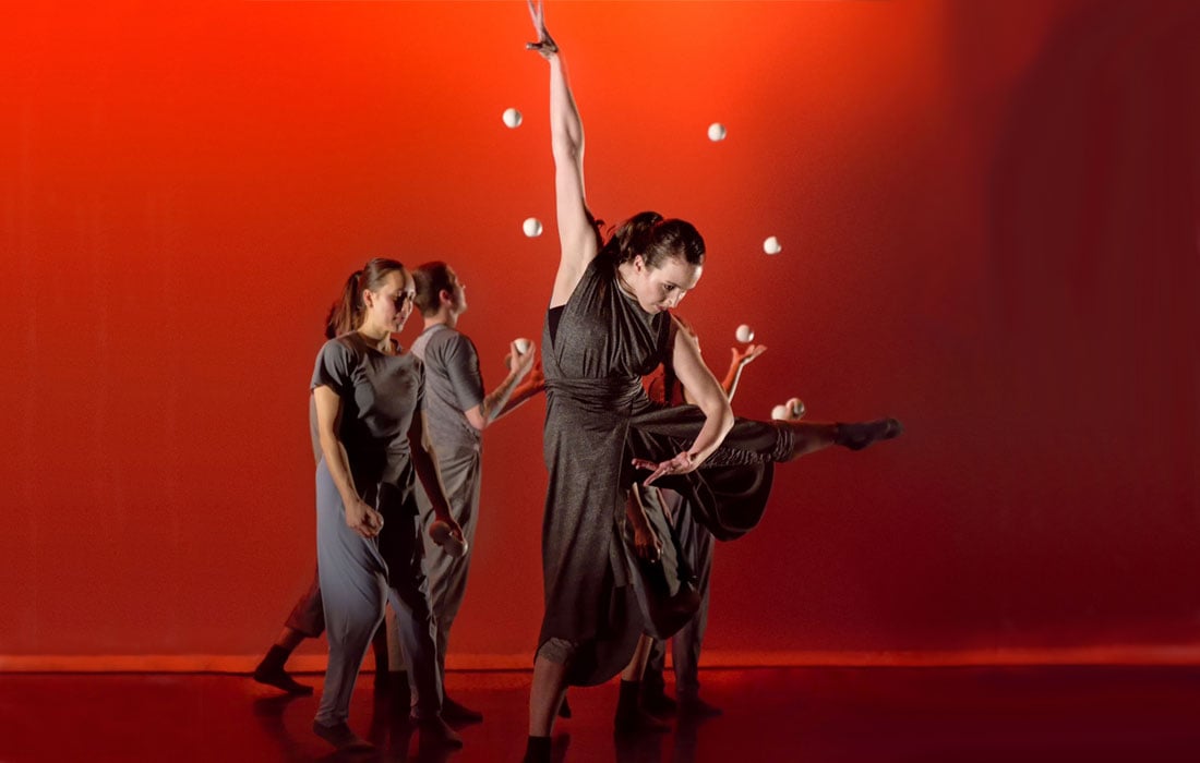 Photo of four performers, two juggling in the background, and the lead dancing in the foreground