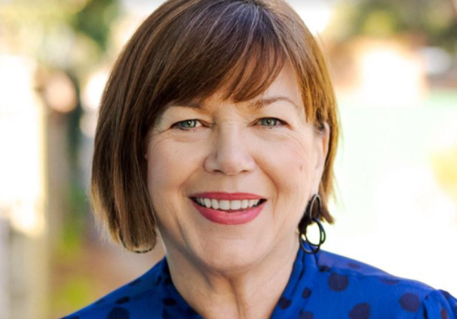 Sharon Burgess, Aberdeen Performing Arts Chief Executive. She is a white woman with short brown hair and a fringe, wearing red lipstick and a blue shirt/dress. She is photographed outside, the background is blurred.