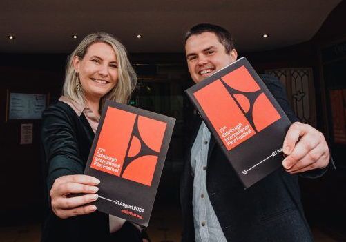 Two people hold leaflets for the Edinburgh International Film Festival