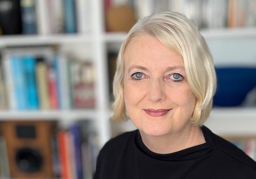 Maureen Corish smiles in front of a bookcase