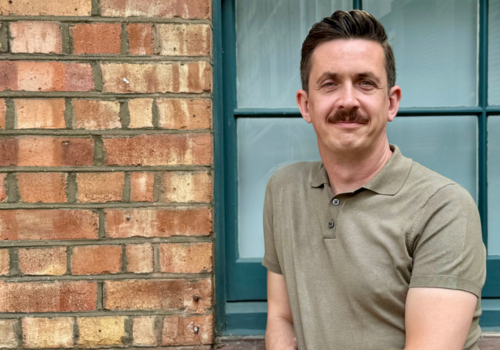 Dan Cowdrill stands next to a brick wall