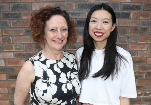 Julia Skelton and Joyce Nga Yu Lee stand in front of a brick wall