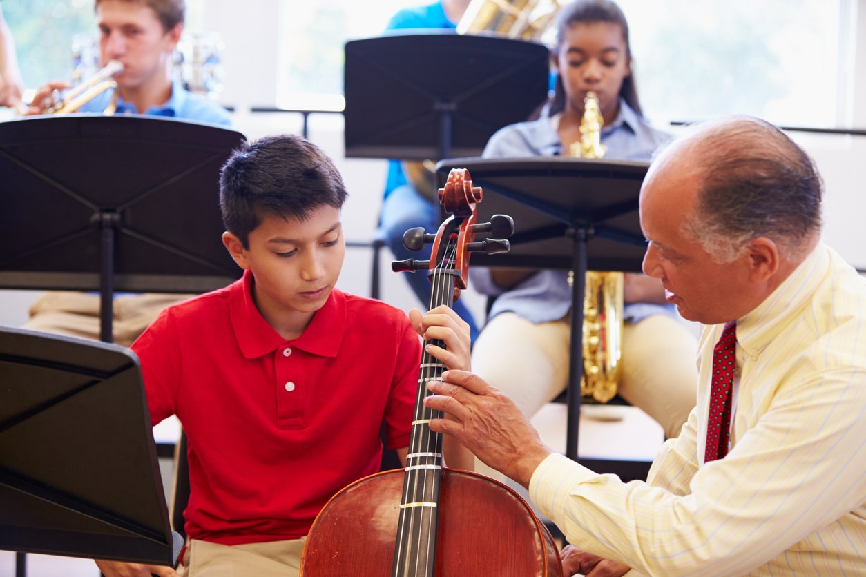 Boy Learning To Play Cello In High School Orchestra iStock