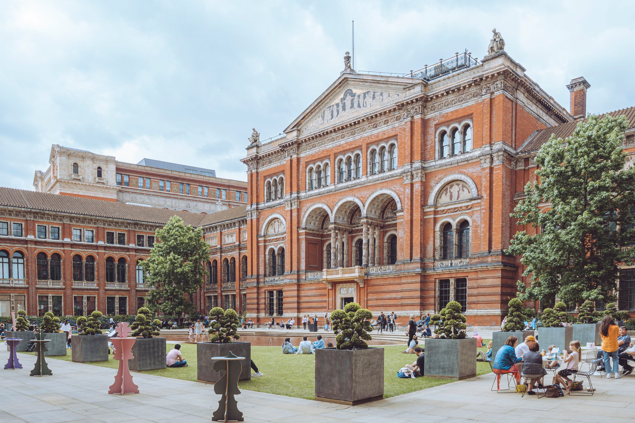 London, United Kingdom – July 11, 2021: A outside view of Victoria and Albert Museum in London, with park in front of it, and people relaxing